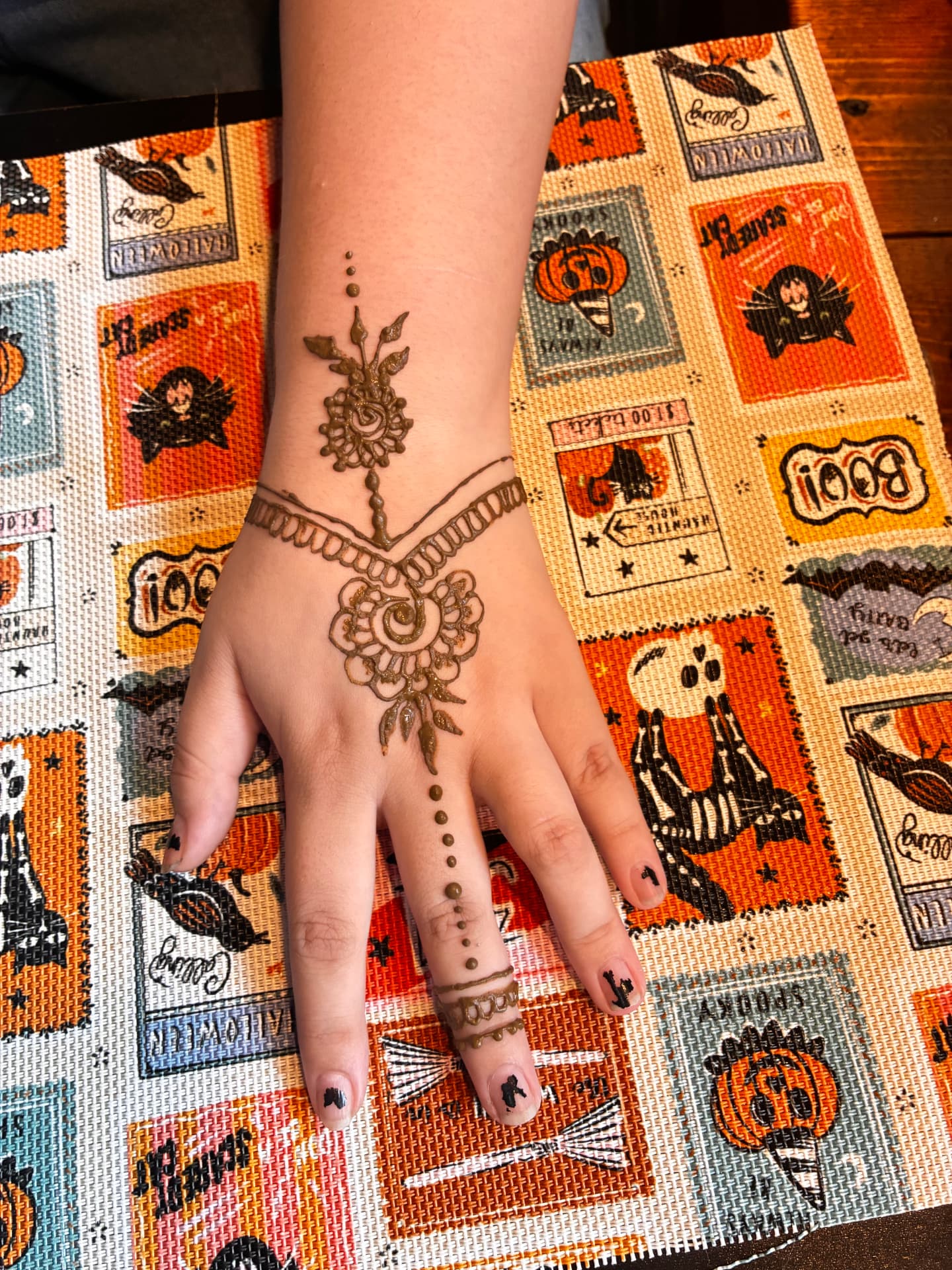 Floral henna cuff and finger chain across a hand and wrist