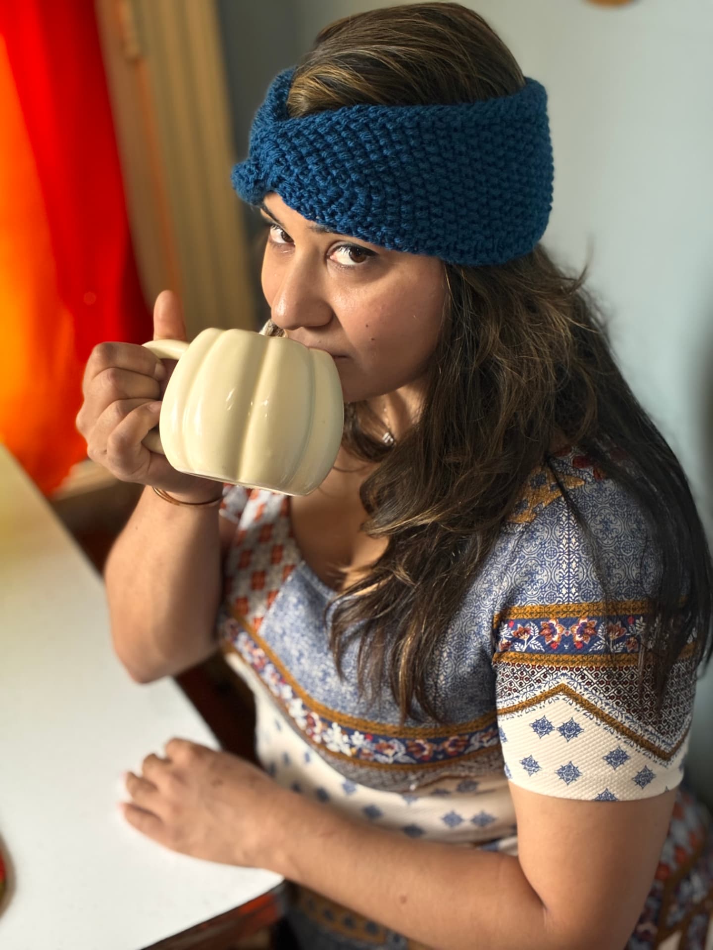 Hand-knit teal headband worn with a warm mug