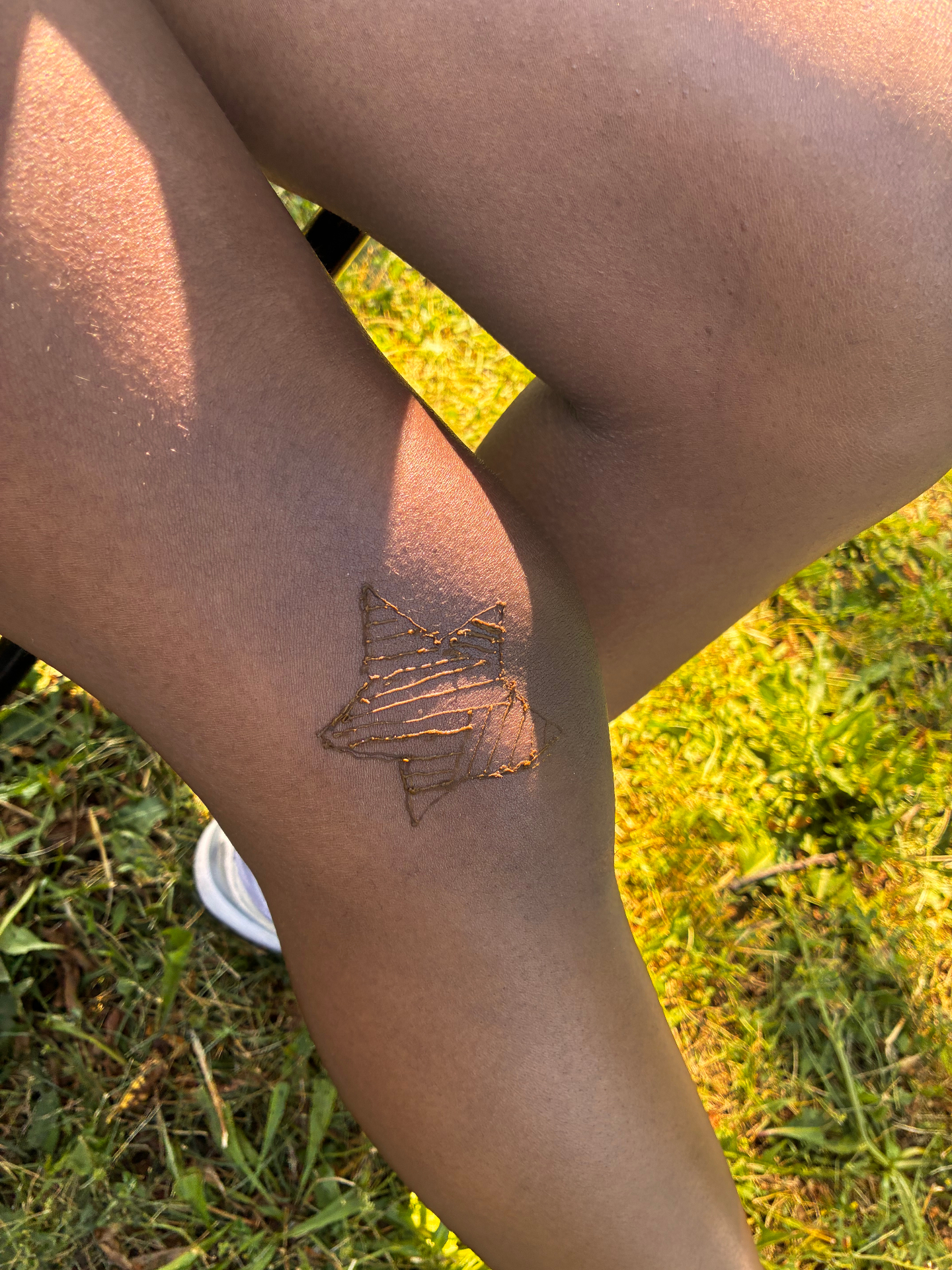 Henna star design on the knee, drying in sunlight